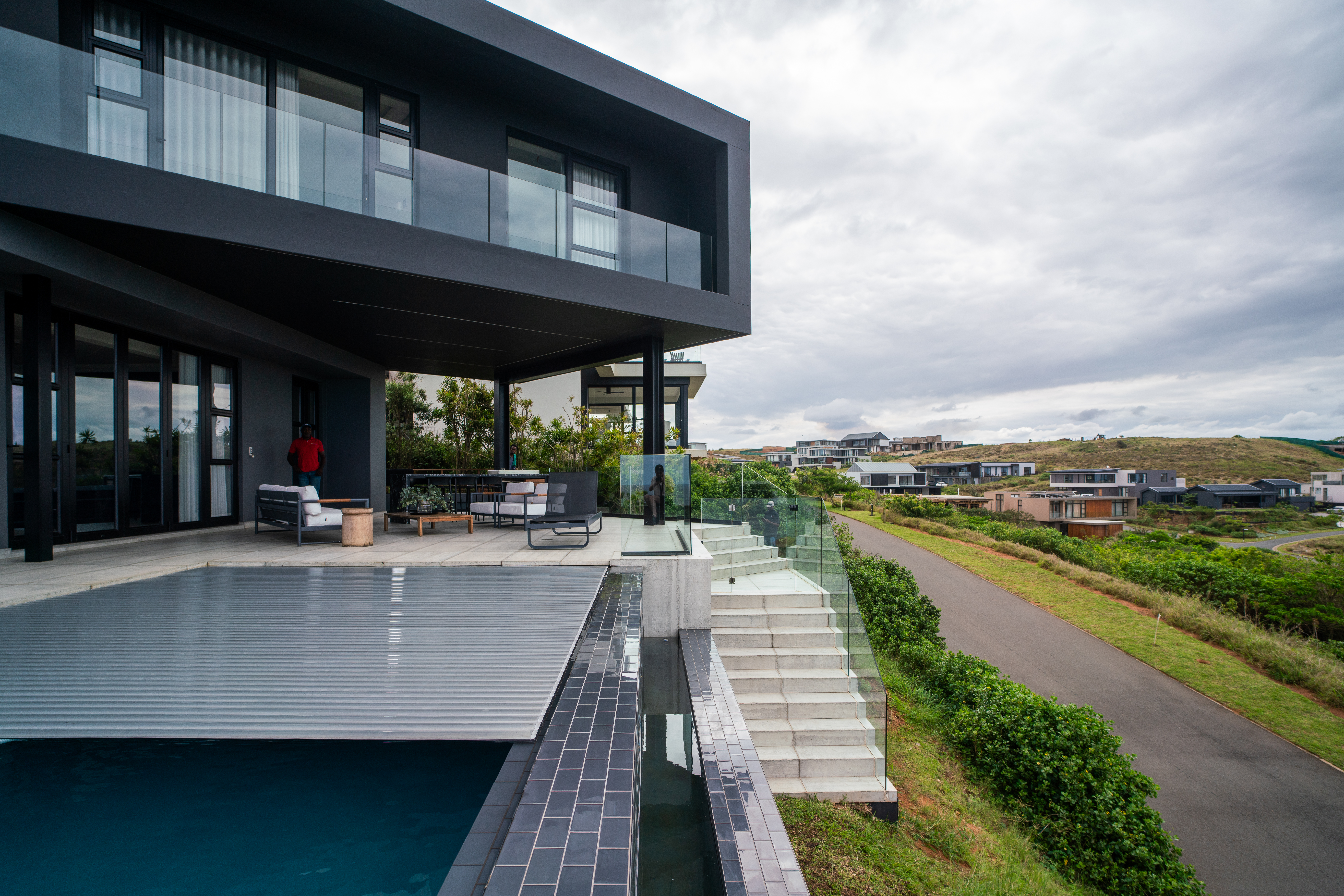 Automatic slatted pool cover system installed on luxury pool deck with scenic view