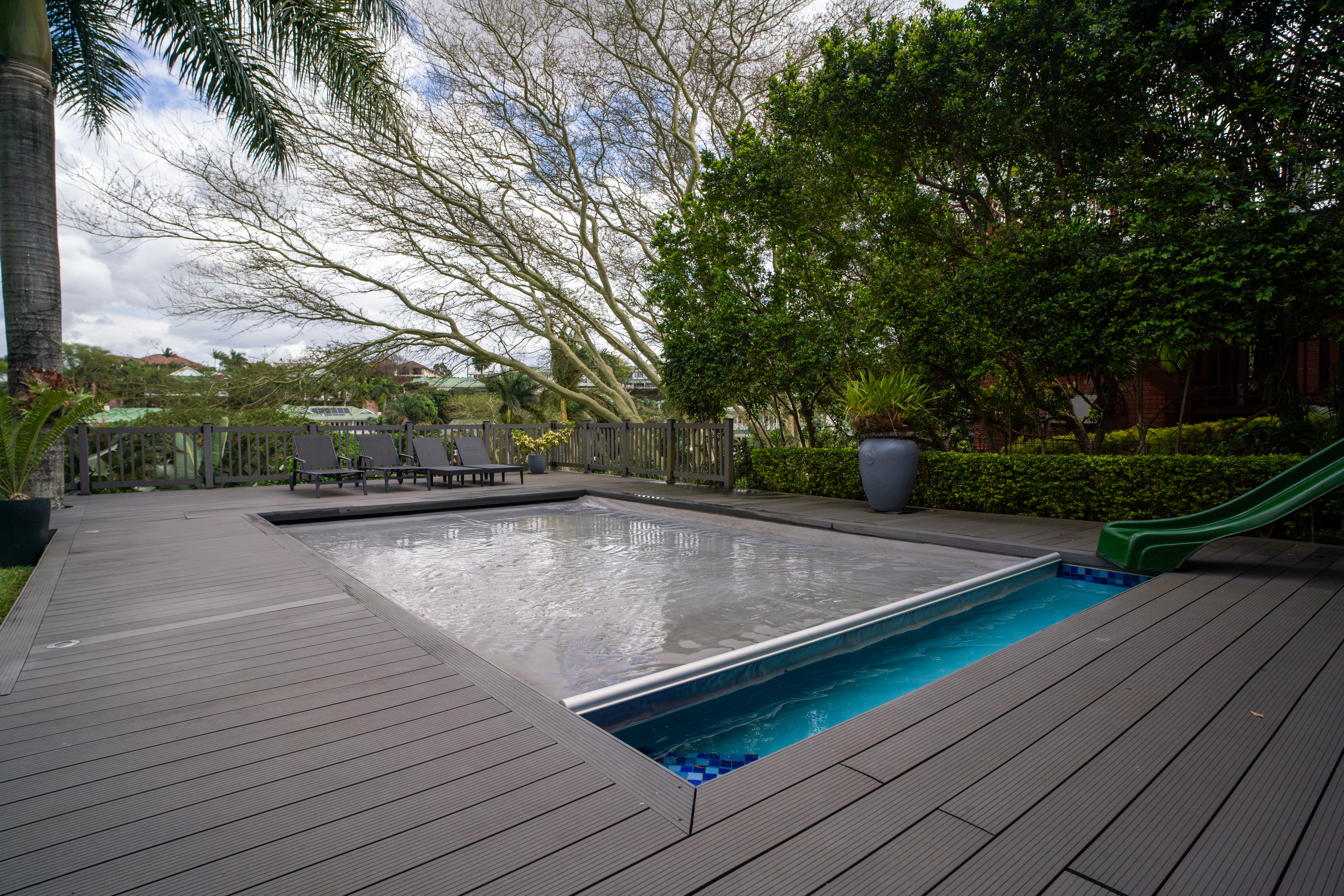 Vinyl automatic pool cover installation on family pool with deck surface showing safety features